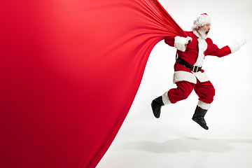 Image showing Santa Claus pulling huge bag full of christmas presents isolated on white background