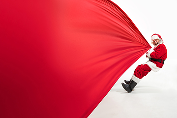 Image showing Santa Claus pulling huge bag full of christmas presents isolated on white background