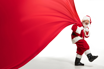 Image showing Santa Claus pulling huge bag full of christmas presents isolated on white background