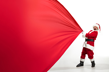 Image showing Santa Claus pulling huge bag full of christmas presents isolated on white background