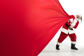 Image showing Santa Claus pulling huge bag full of christmas presents isolated on white background