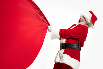 Image showing Santa Claus pulling huge bag full of christmas presents isolated on white background