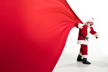 Image showing Santa Claus pulling huge bag full of christmas presents isolated on white background