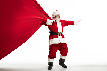 Image showing Santa Claus pulling huge bag full of christmas presents isolated on white background