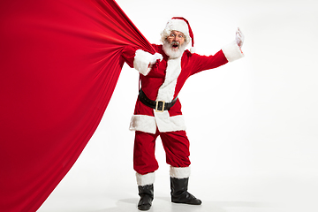 Image showing Santa Claus pulling huge bag full of christmas presents isolated on white background