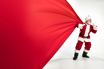 Image showing Santa Claus pulling huge bag full of christmas presents isolated on white background