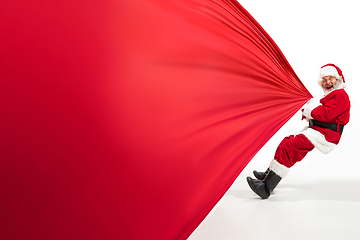 Image showing Santa Claus pulling huge bag full of christmas presents isolated on white background