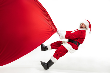 Image showing Santa Claus pulling huge bag full of christmas presents isolated on white background