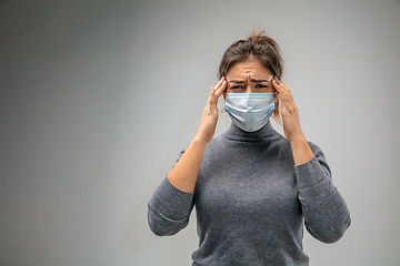 Image showing Caucasian woman wearing the respiratory protection mask against air pollution and dusk on grey studio background