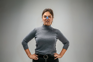 Image showing Caucasian woman wearing the respiratory protection pin clasp against air pollution and dusk on grey studio background