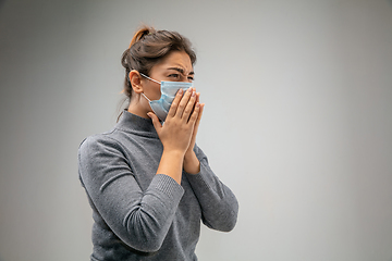 Image showing Caucasian woman wearing the respiratory protection mask against air pollution and dusk on grey studio background