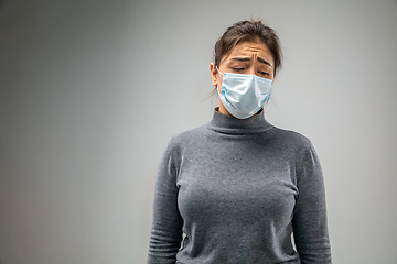 Image showing Caucasian woman wearing the respiratory protection mask against air pollution and dusk on grey studio background