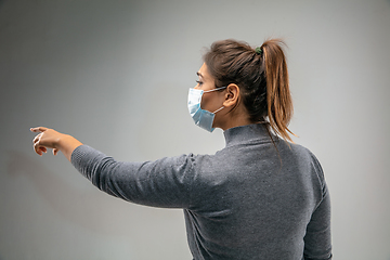 Image showing Caucasian woman wearing the respiratory protection mask against air pollution and dusk on grey studio background