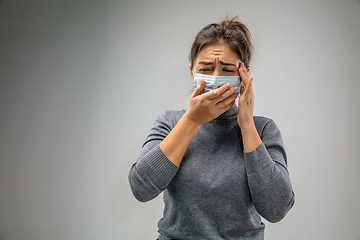 Image showing Caucasian woman wearing the respiratory protection mask against air pollution and dusk on grey studio background