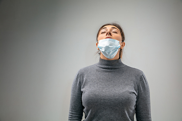 Image showing Caucasian woman wearing the respiratory protection mask against air pollution and dusk on grey studio background