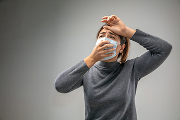 Image showing Caucasian woman wearing the respiratory protection mask against air pollution and dusk on grey studio background