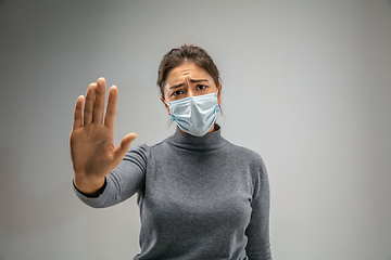 Image showing Caucasian woman wearing the respiratory protection mask against air pollution and dusk on grey studio background