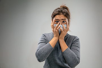 Image showing Caucasian woman wearing the respiratory protection mask against air pollution and dusk on grey studio background