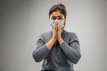 Image showing Caucasian woman wearing the respiratory protection mask against air pollution and dusk on grey studio background