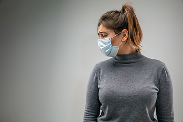 Image showing Caucasian woman wearing the respiratory protection mask against air pollution and dusk on grey studio background