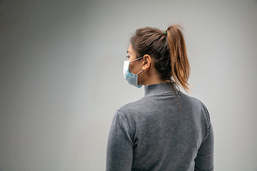 Image showing Caucasian woman wearing the respiratory protection mask against air pollution and dusk on grey studio background