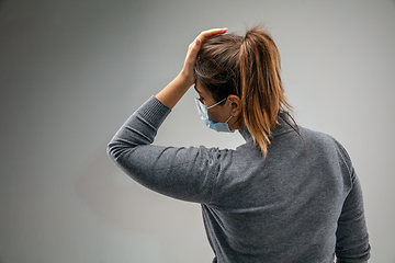 Image showing Caucasian woman wearing the respiratory protection mask against air pollution and dusk on grey studio background