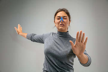 Image showing Caucasian woman wearing the respiratory protection pin clasp against air pollution and dusk on grey studio background