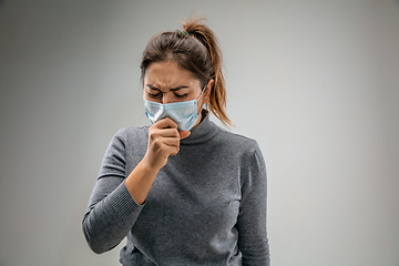 Image showing Caucasian woman wearing the respiratory protection mask against air pollution and dusk on grey studio background