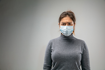 Image showing Caucasian woman wearing the respiratory protection mask against air pollution and dusk on grey studio background