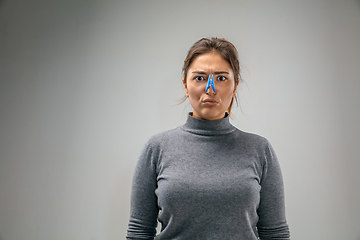 Image showing Caucasian woman wearing the respiratory protection pin clasp against air pollution and dusk on grey studio background