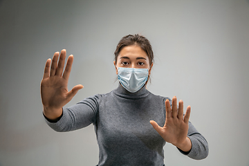 Image showing Caucasian woman wearing the respiratory protection mask against air pollution and dusk on grey studio background