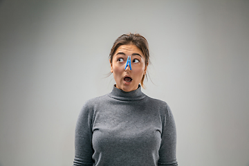 Image showing Caucasian woman wearing the respiratory protection pin clasp against air pollution and dusk on grey studio background