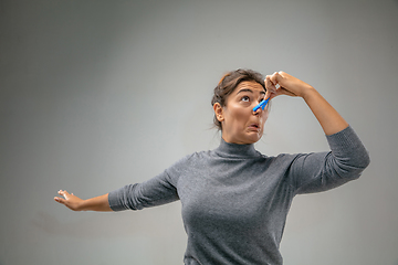 Image showing Caucasian woman wearing the respiratory protection pin clasp against air pollution and dusk on grey studio background