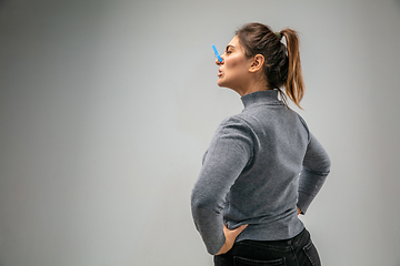 Image showing Caucasian woman wearing the respiratory protection pin clasp against air pollution and dusk on grey studio background