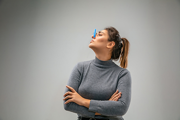 Image showing Caucasian woman wearing the respiratory protection pin clasp against air pollution and dusk on grey studio background