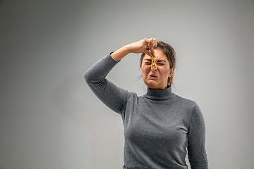 Image showing Caucasian woman wearing the respiratory protection pin clasp against air pollution and dusk on grey studio background