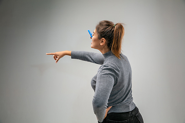 Image showing Caucasian woman wearing the respiratory protection pin clasp against air pollution and dusk on grey studio background