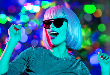 Image showing happy woman in pink wig and sunglasses dancing