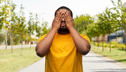 Image showing african american man closing his eyes by hands