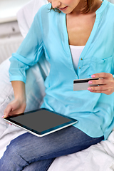 Image showing happy woman with tablet pc and credit card at home