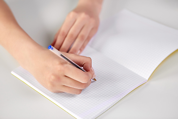 Image showing hands of student girl with pen writing to notebook