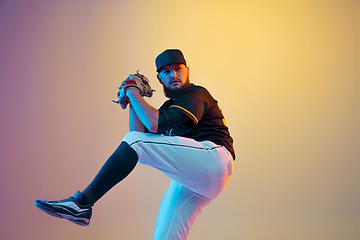 Image showing Baseball player, pitcher in a black uniform practicing on gradient background in neon light