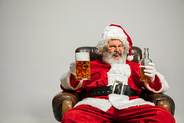 Image showing Santa Claus drinking beer sitting on armchair, congratulating of New Year 2020