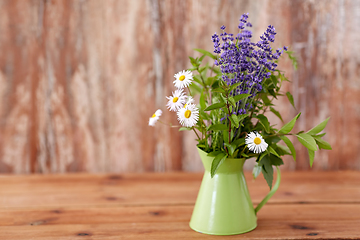 Image showing bunch of herbs and flowers in green jug on table