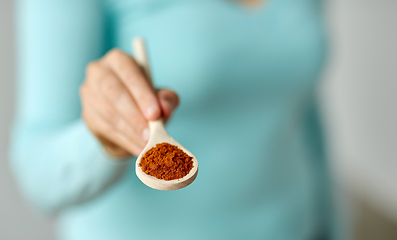 Image showing close up of woman with turmeric on wooden spoon