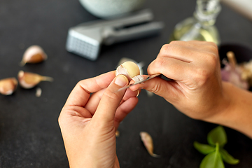 Image showing hands peeling garlic with knife for pesto sauce