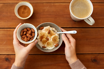 Image showing hands with oatmeal breakfast and cup of coffee