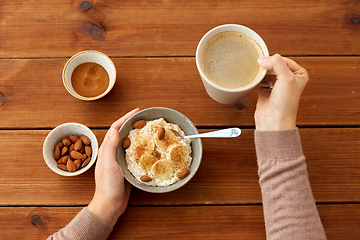 Image showing hands with oatmeal breakfast and cup of coffee