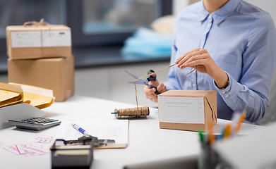 Image showing woman with parcel cutting rope at post office