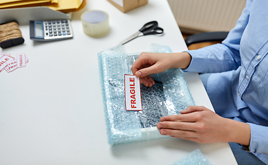 Image showing woman sticking fragile mark to wrap at post office